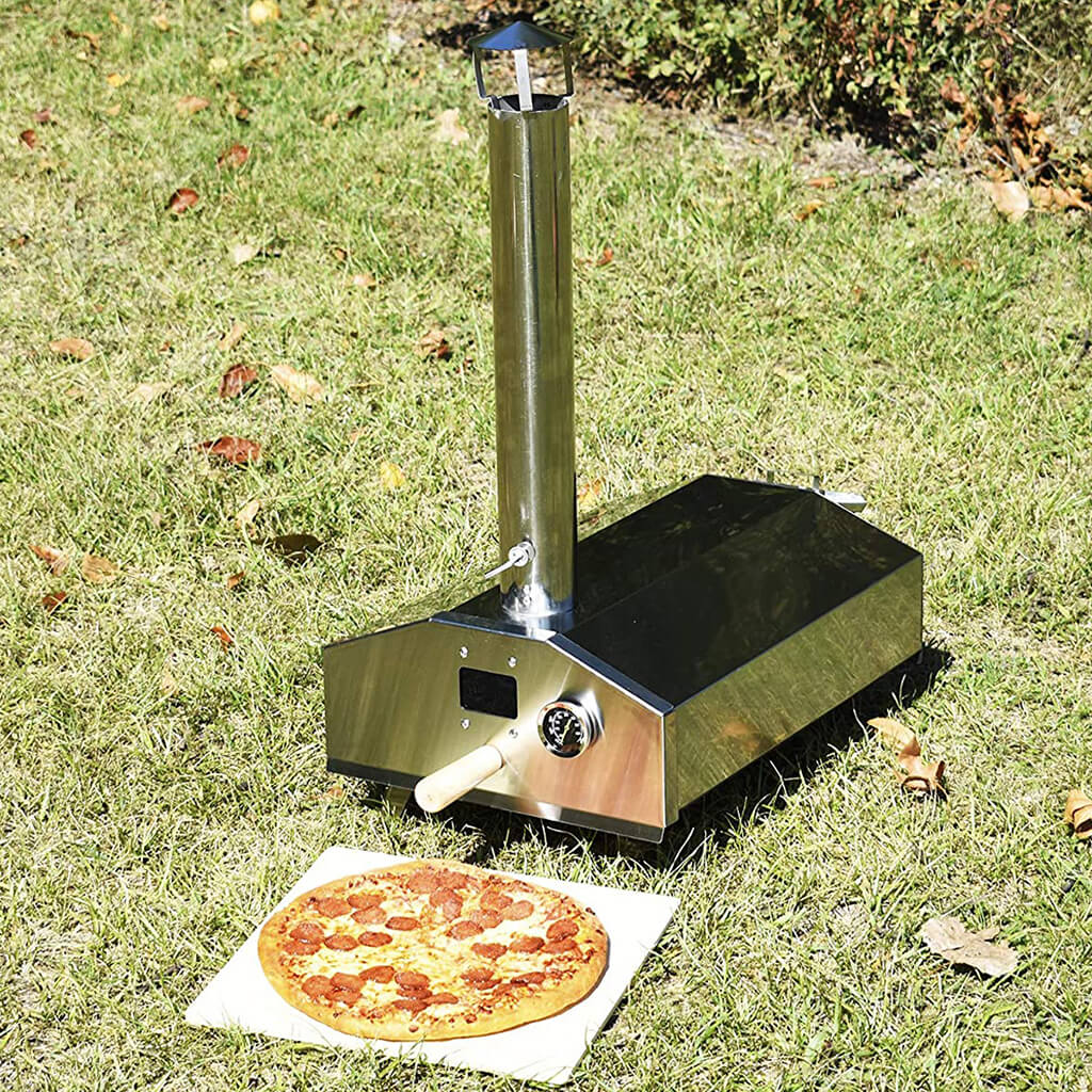 Compact camping pizza oven on grass with a pepperoni pizza