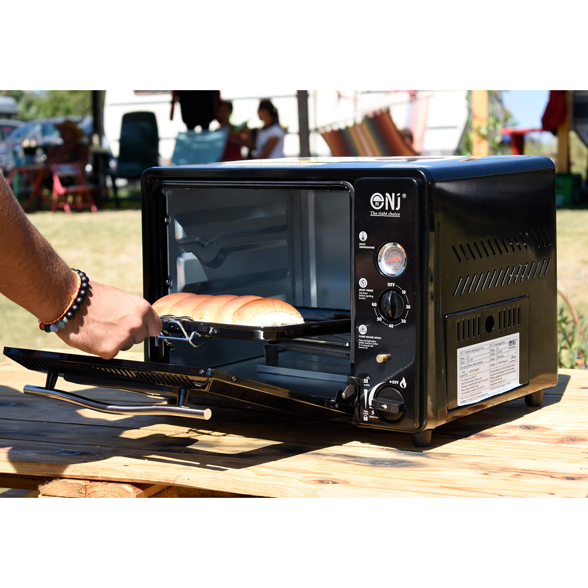 Black outdoor toaster oven with a person placing bread inside outdoor