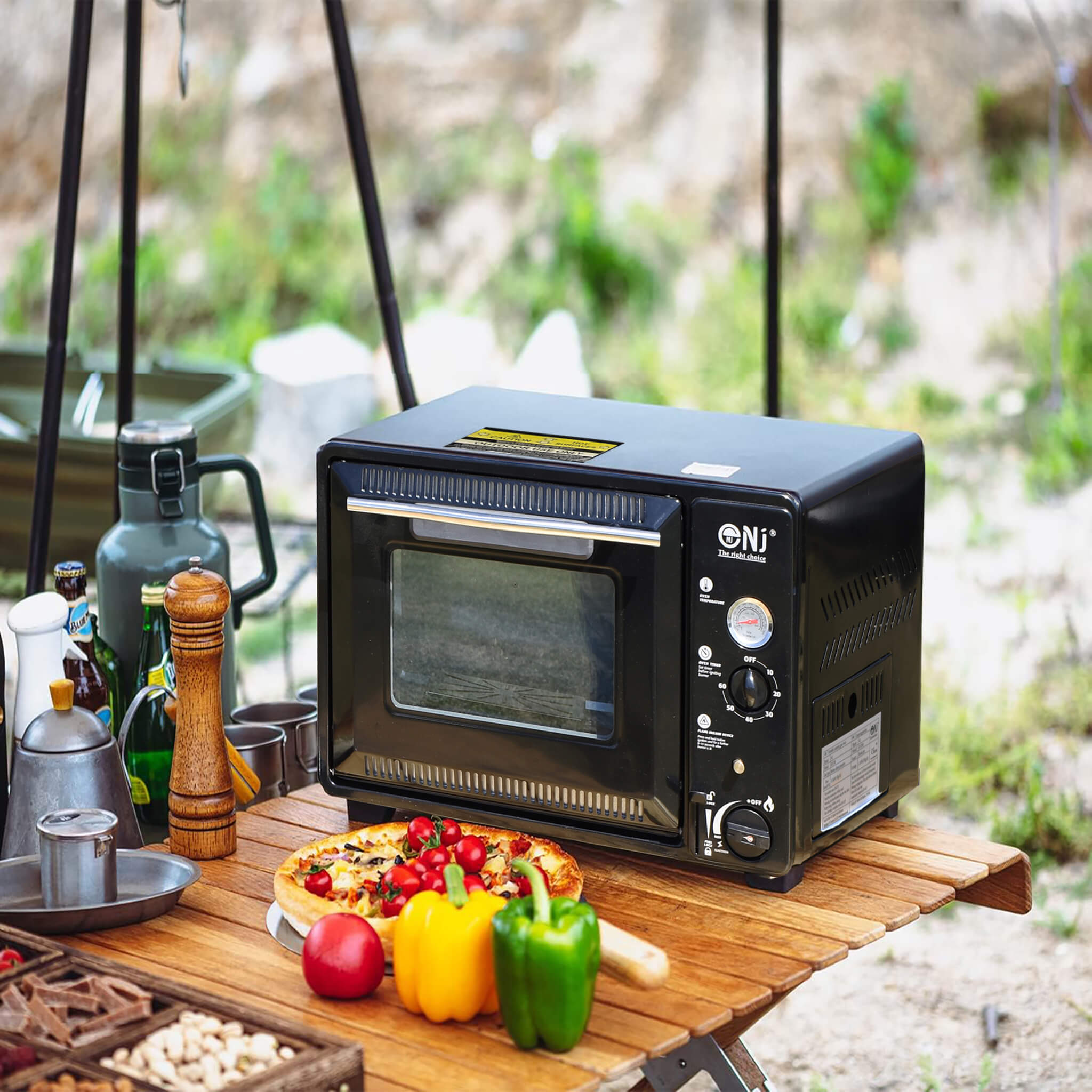 Portable oven on a wooden table with food and drinks outdoors