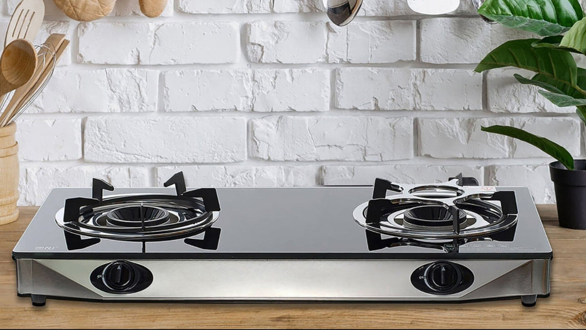 Modern kitchen with black stove, hanging utensils, and a white brick wall.