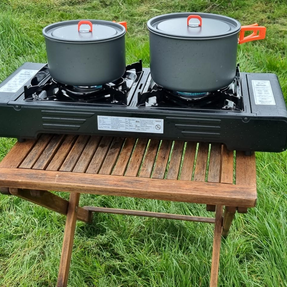 Portable camping stove with two pots on a grassy background