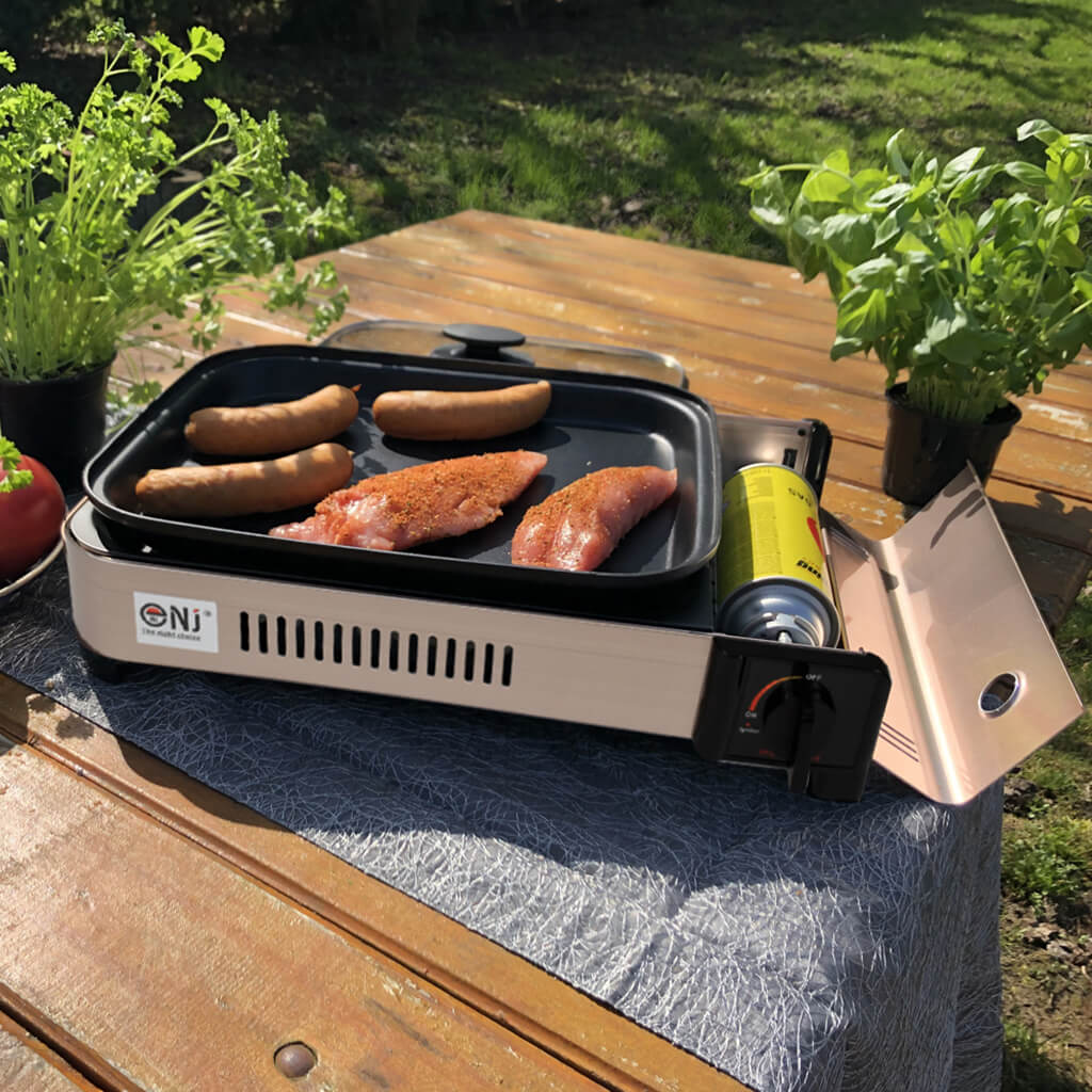 Portable grill with food on a wooden table outdoors